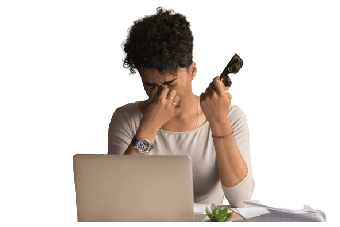 woman rubbing her irritated eyes in front of a laptop